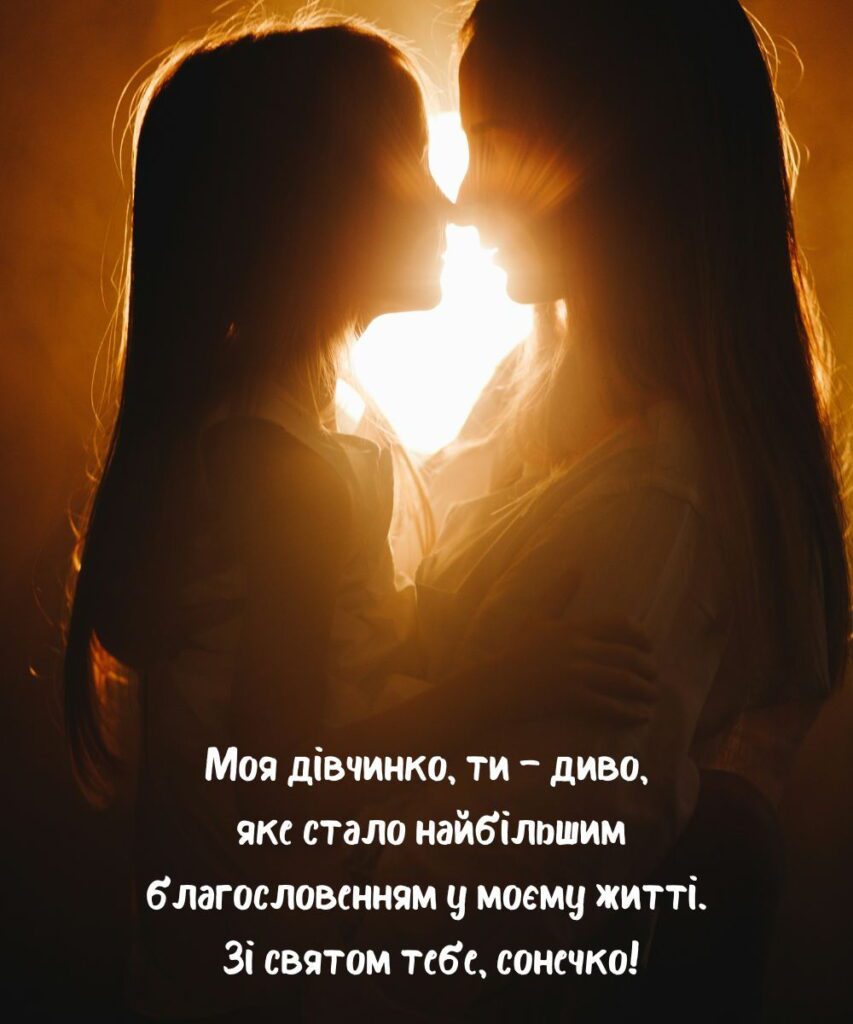 Мама і донька обіймаються на фоні заходу сонця