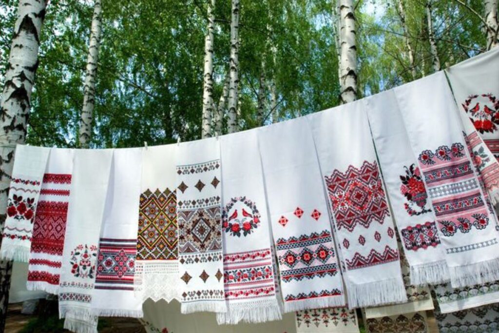 Багато рушників з українським орнаментом висять на вулиці на шнурку між березами
