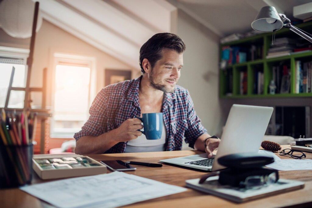 Чоловік надає онлайн-послуги за ноутбуком у домашньому офісі з чашкою кави