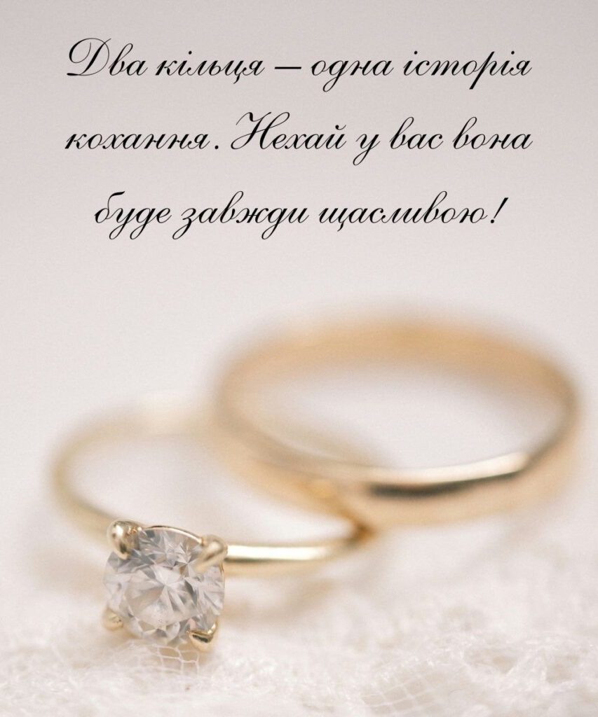 Пара обручок на світлому фоні та привітання з річницею весілля
