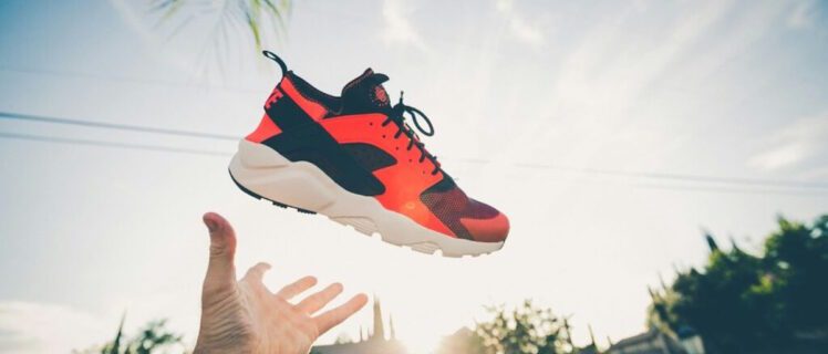 Рука підкидає кросівок у повітря