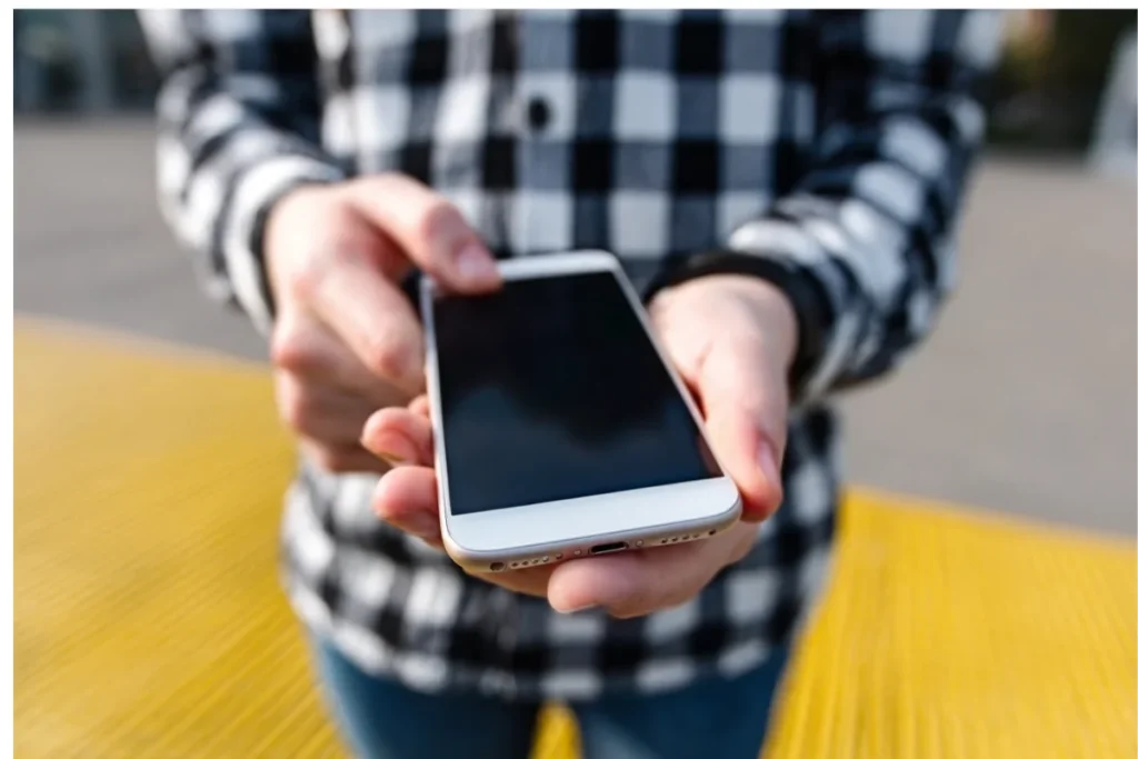 Айфон у руках, екран вимкнений, вигляд знизу