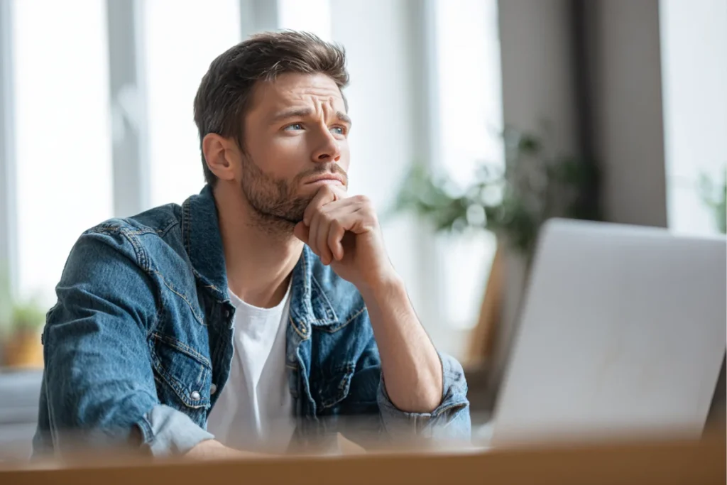 Чоловік думає над доставкою, дивлячись у ноутбук