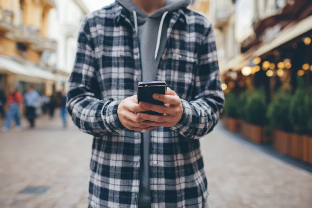 Людина тримає Айфон і користується ним на вулиці